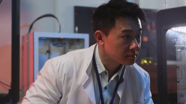 Asian technician finetunes printer, Asian engineer carefully adjusting prototype threedimensional printing device