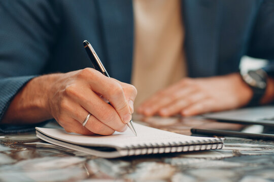 A businessman writes a business plan in a notebook. A man handwriting an idea with a ballpoint pen.