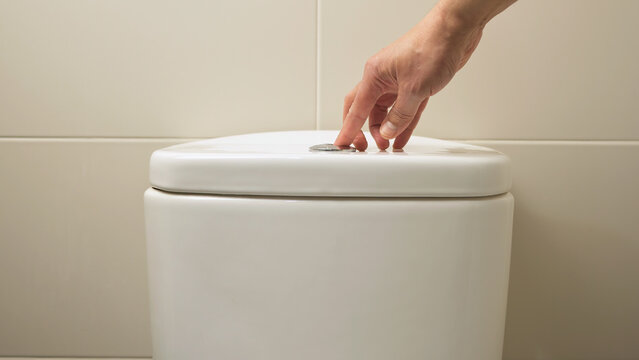 Hand pushing a button to flush a close tool at home