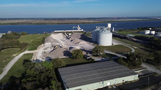 Bulk handling site along Virginia Ave near Cooper River and North Charleston Terminal shows active port side operations. Conveyor lines, pale aggregate piles, metal textures in South Carolina