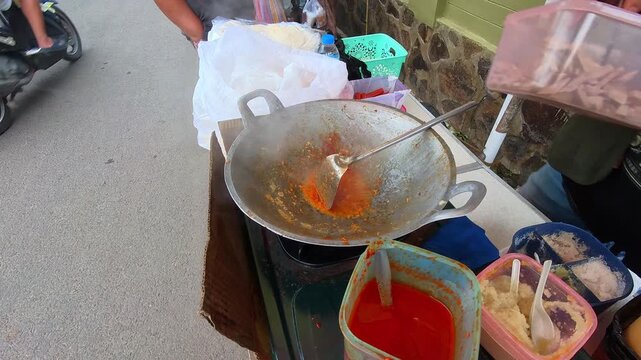 Video of a street food vendor hand seasoning stir-fried bean sprouts and eggs with spicy seasoning. Top-angle footage of the vendor cooking the dish for customers. Steady 4K High Resolution