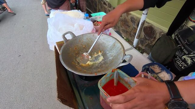Video of a street food vendor hand seasoning stir-fried bean sprouts and eggs with spicy seasoning. Top-angle footage of the vendor cooking the dish for customers. Steady 4K High Resolution