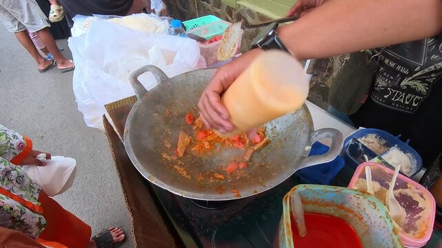 Video of a street food vendor hand seasoning stir-fried bean sprouts and eggs with spicy seasoning. Top-angle footage of the vendor cooking the dish for customers. Steady 4K High Resolution