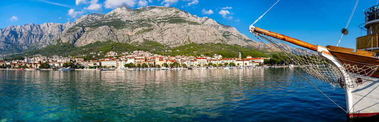Croatia Makarska Riviera 11K Panorama Close Up of Traditional Wooden Yacht Bow with Scenic Old Town and Biokovo Mountains Background Luxury Nautical Travel Lifestyle Adriatic Coast