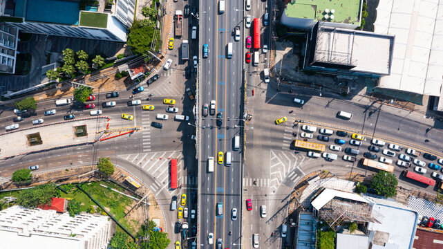 Top view of busy urban intersection with multiple lanes of traffic and vehicles moving through city roads, capturing transportation flow and modern infrastructure in daylight.