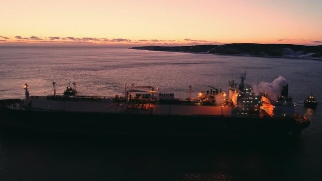 A large LNG tanker docks at an industrial port terminal for cargo operations at dusk