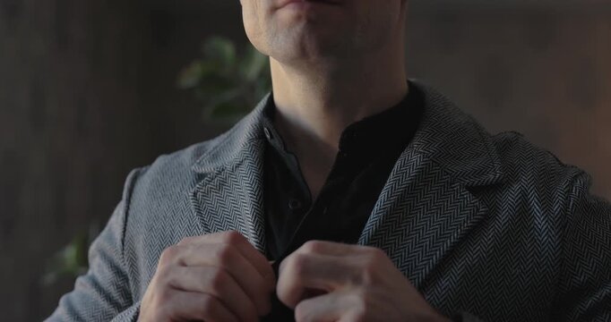 A man buttons his shirt and straightens a jacket