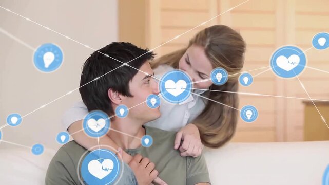 Animation of network of connections with icons over caucasian couple embracing on sofa
