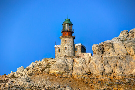 Akra Lithari lighthouse standing on rugged cape rocks under clear blue sky, in Skyros island, Greece