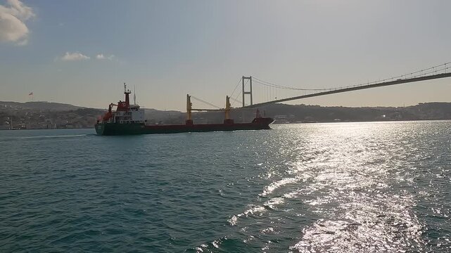 Sea freight and transport logistics. Passage of cargo ships and tankers through the Bosphorus Strait. Cargo ship tanker in Bosphorus Strait about to pass under Bosphorus bridge. Shipping 