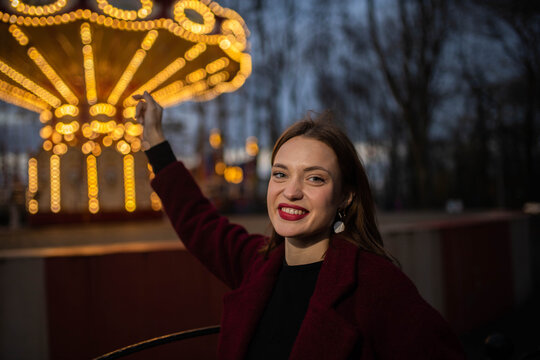 A woman is enjoying herself at an amusement park in the evening