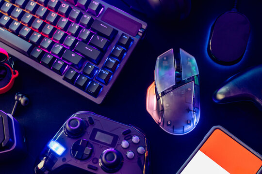 gamer work space concept, top view a gaming gear, mouse, keyboard, joystick, and headset with rgb color on black table background.