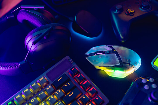 gamer work space concept, top view a gaming gear, mouse, keyboard, joystick, and headset with rgb color on black table background.