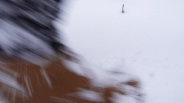 A man walking on big snow in cold winter wearing brown boots in the evening, top view, lost in the forest