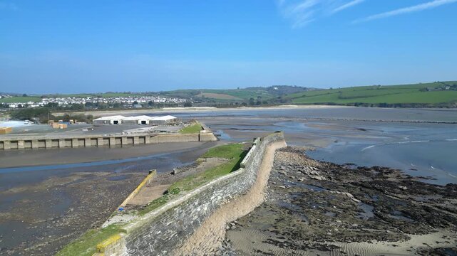 Par, Cornwall, England: DRONE VIEWS: The drone rises over Par Docks harbour wall to reveal Par Sands beach and the town of Par. Par is a fishing port which developed as a harbour in the 19th century.