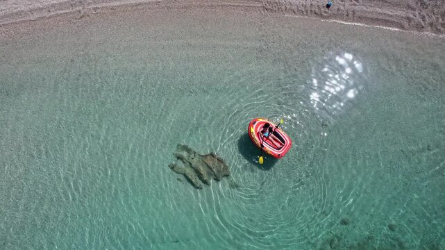 Child enjoy paddling in an inflatable rubber boat on a calm shallow summer beach