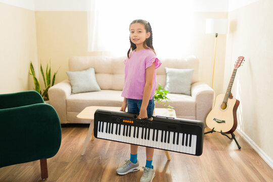 Full length view of a girl carrying a keyboard at home, learning to play music, developing artistic talent and creativity