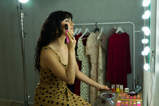 Model applying makeup at a vanity table backstage, preparing for a fashion show or important event