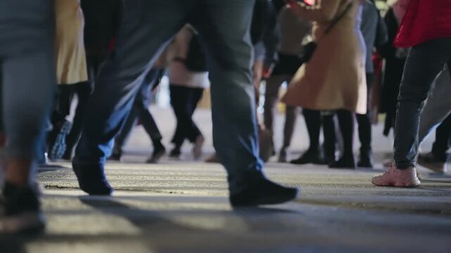 Busy pedestrians walking across a city street at night in urban Athens