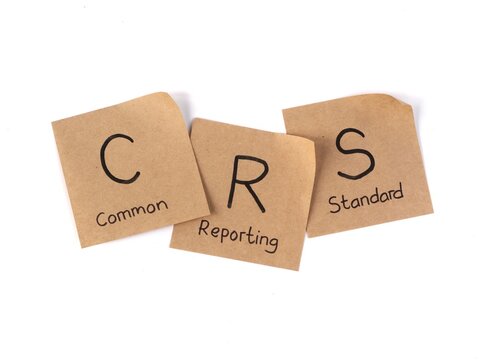 Common Reporting Standard (CRS) acronym handwritten on brown paper notes on white background. Concept of financial transparency and global banking regulations against tax evasion