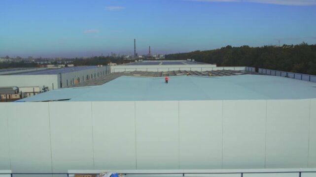 Workers applying waterproof coating on rooftop, Wide aerial shot of roof insulation and construction staff