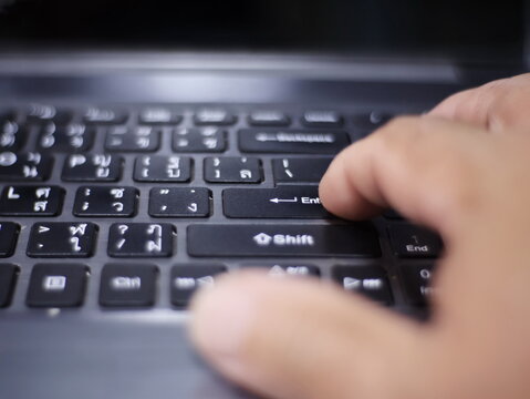 An image of a hand pressing the "Enter" key on a black laptop keyboard.