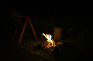 Bright campfire burning with wood logs and stones at night in an outdoor camping area. Concept of adventure, warmth, relaxation, nature travel, and cozy lifestyle.