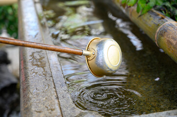 Japanese metal dipper for ritual cleansing at the entrance to the Japanese Buddhist temple. who visit the shrine to clean their mouth, hands, and faces.