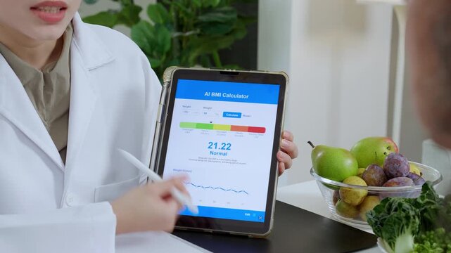 Asian woman nutritionist showing AI BMI calculator on tablet and explaining to senior patient, doctor using digital health technology for medical diagnosis, wellness planning and weight control.