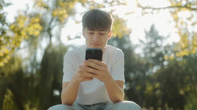 Young Boy on Park Bench Pulling Out Phone, Enjoying Nature and Digital Life