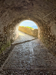 Fototapeta premium Stone tunnel and cobblestone path inside Corfu island New Fortress, Greece. Bright day light at the exit