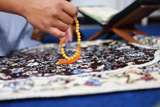 Close-up of hands reciting dhikr using prayer beads against a blurred background. Hands reciting dhikr. A man reciting dhikr while holding a prayer beads. A Muslim's worship activity.
