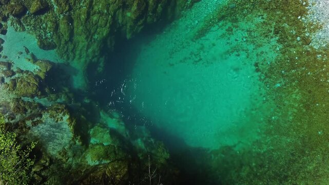 Aerial top view of turquoise spring water surrounded by lush green forest, Oko Skakavice in Montenegro, 4k