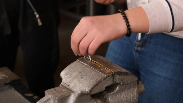 A person is using a hammer to strike a metal object