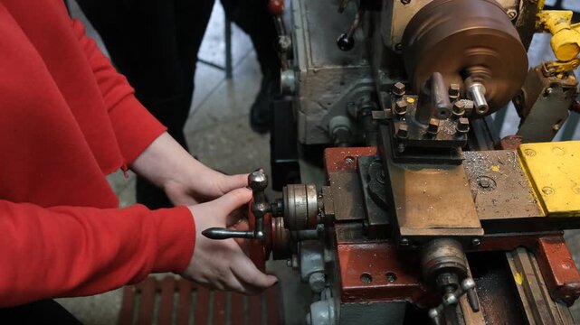 A woman is working on a machine that is working with a lathe