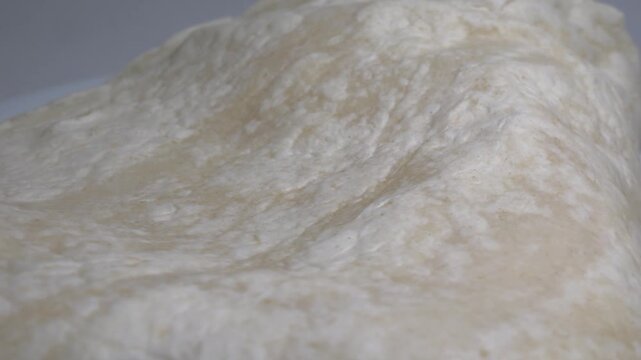 Close-up of a stack of fresh, thin flour tortillas or flatbreads on a white plate, captured on a rotating surface against a neutral background.