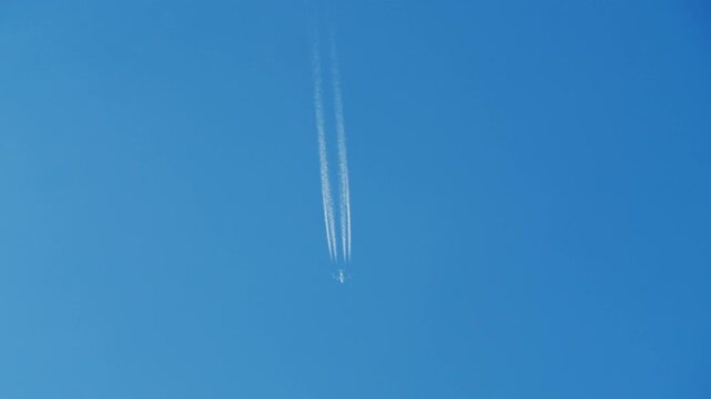 Civil four-engine airplane crosses the sky leaving a trail of smoke. Tourism and travel concept
