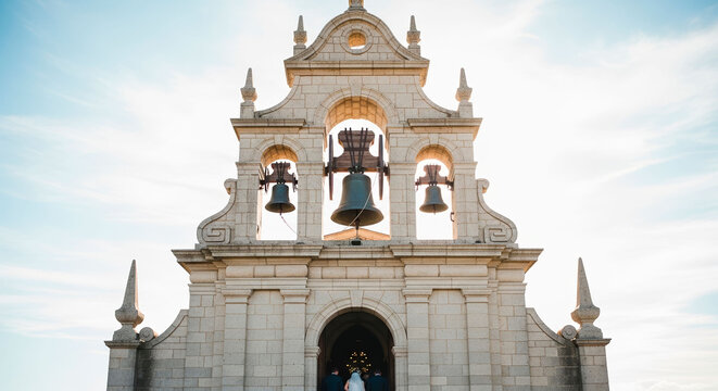 Church wedding displaying an old historic stone facade with tall bell towers. The majestic building stands as a breathtaking destination for a religious matrimony ceremony.