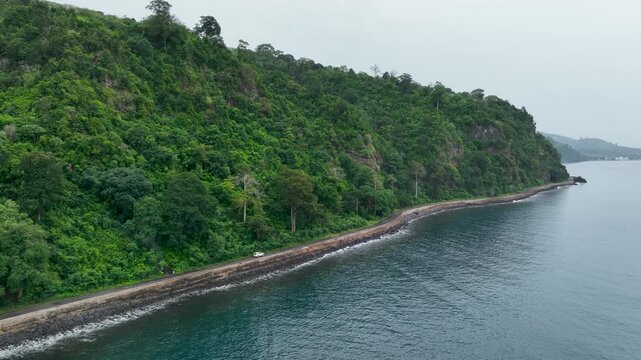 Car driving on ocean seaside road on S&atilde;o Tom&eacute; and Pr&iacute;ncipe, drone perspective