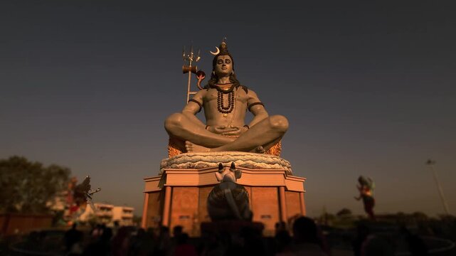 Massive statue of Lord Shiva with trishul at Char Dham Temple in Vrindavan, India, set against a clear blue sky. This iconic spiritual landmark represents meditation.