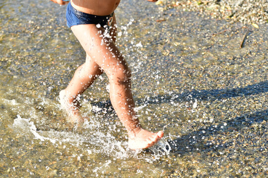 Kind an einem See, hat Spa&szlig; und springt durchs Wasser und spritzt