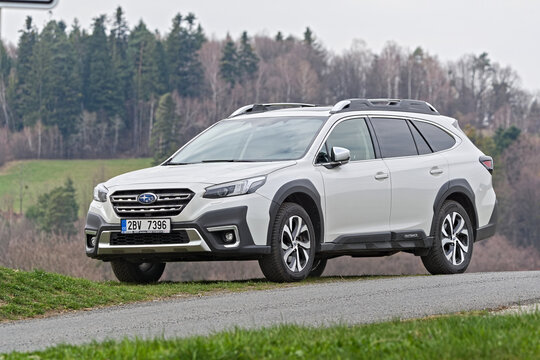 Subaru Outback parked on rural road with countryside landscape in background