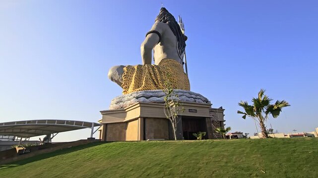 Massive statue of Lord Shiva with trishul at Char Dham Temple in Vrindavan, India, set against a clear blue sky. This iconic spiritual landmark represents meditation.