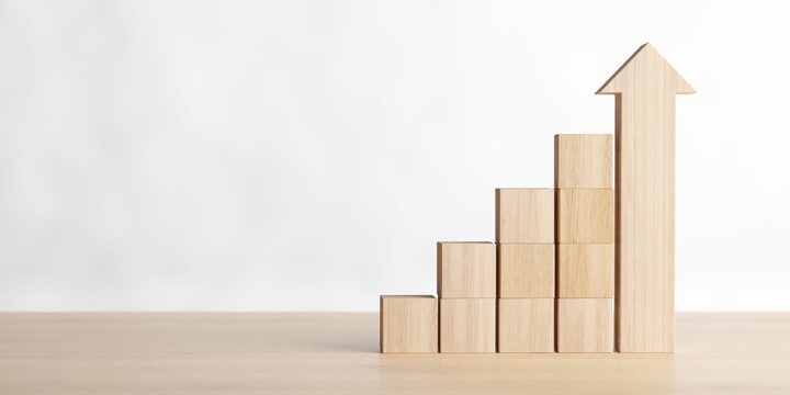 Rising wooden blocks bar graph with biggest one as an arrow on wooden table, business development, increase or career success concept