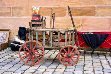 Vintage wooden cart with red wheels filled with juggling clubs and street performer props. Concept of traveling circus, retro fair and entertainment. © beautiful-photo.de
