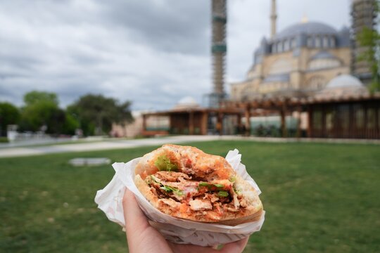 Travel t&uuml;rkiye edirne hand holding street food sandwich with mosque background in edirne