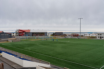 Outdoor Soccer Field with Coastal Town and Cloudy Sky Horizon © heerim studio