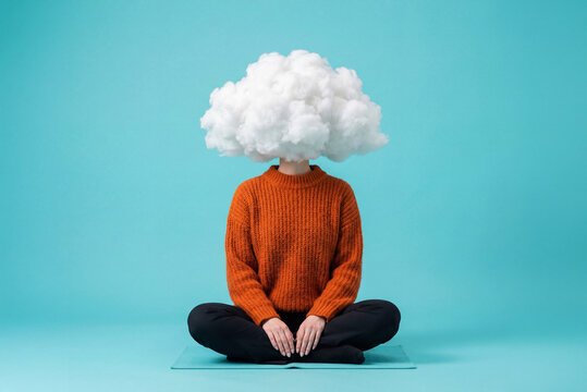 Minimalist surrealism of person with cloud instead of head sitting in lotus pose as symbol of inner peace and letting go of heavy thoughts and routine. Self-care