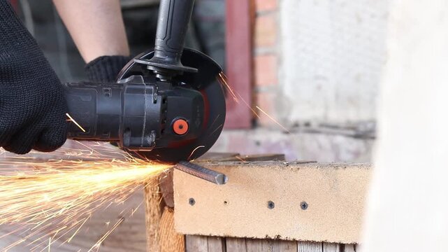 Cordless angle grinder cuts rebar. Sparks fly when cutting rebar with a grinder, construction work close-up. Electric tool for construction and repair work. Grinding machine with metal disc