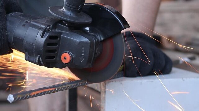 Cordless angle grinder cuts rebar. Sparks fly when cutting rebar with a grinder, construction work close-up. Electric tool for construction and repair work. Grinding machine with metal disc
